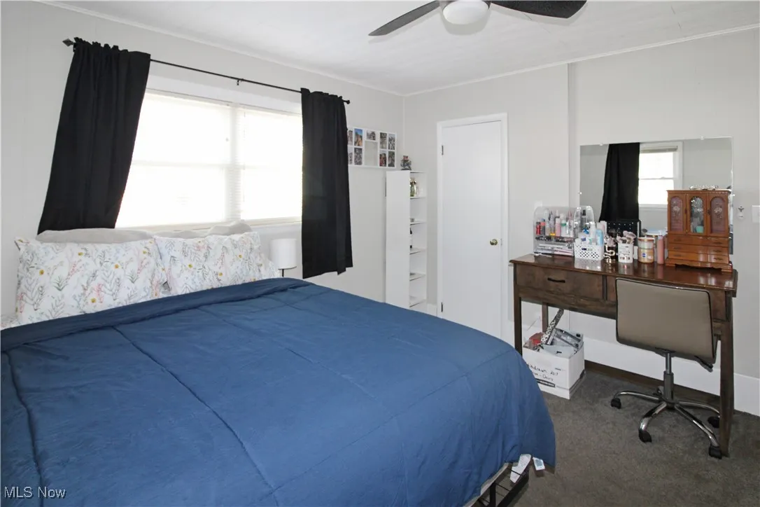 Bedroom featuring dark carpet, ceiling fan, and ornamental molding
