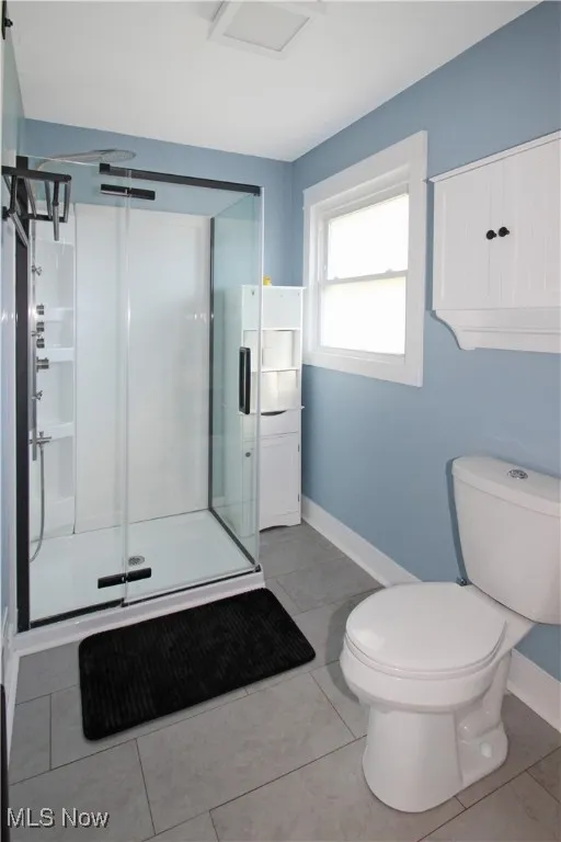 Full bath with a stall shower and light tile patterned flooring
