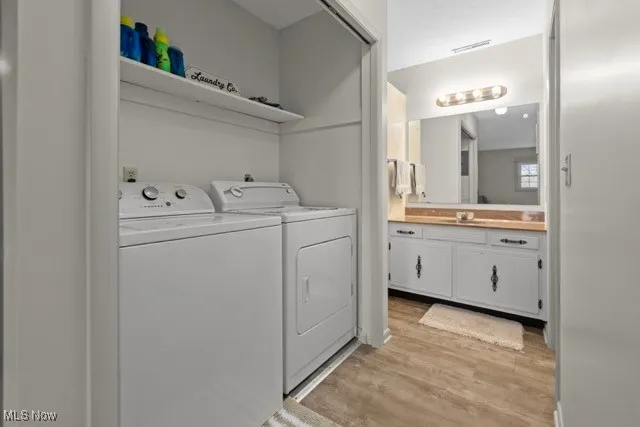 Washroom featuring washer and clothes dryer and light wood-type flooring