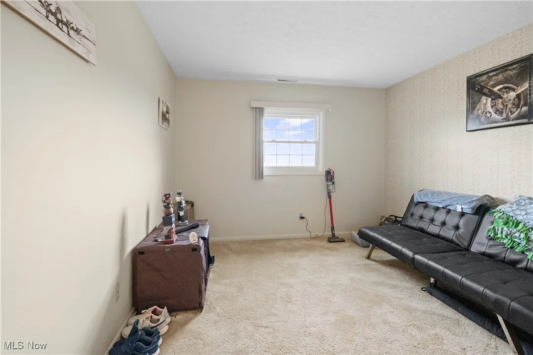 Living area with carpet floors, wallpapered walls, and a textured ceiling