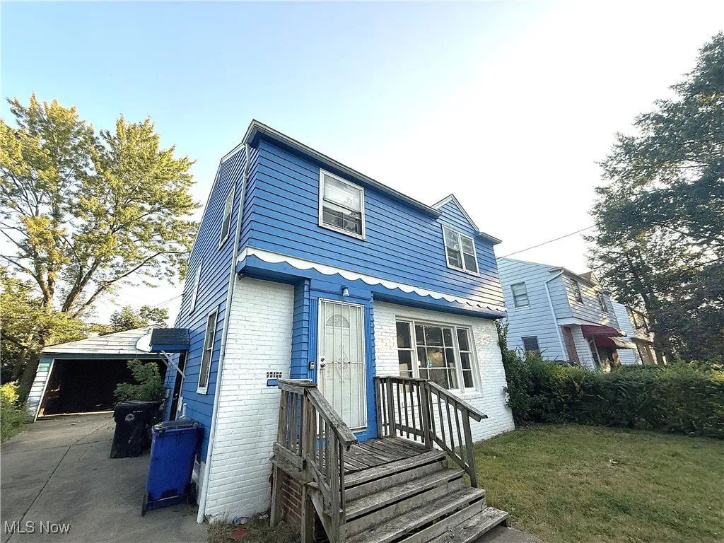 Back of property with brick siding, a garage, and a lawn