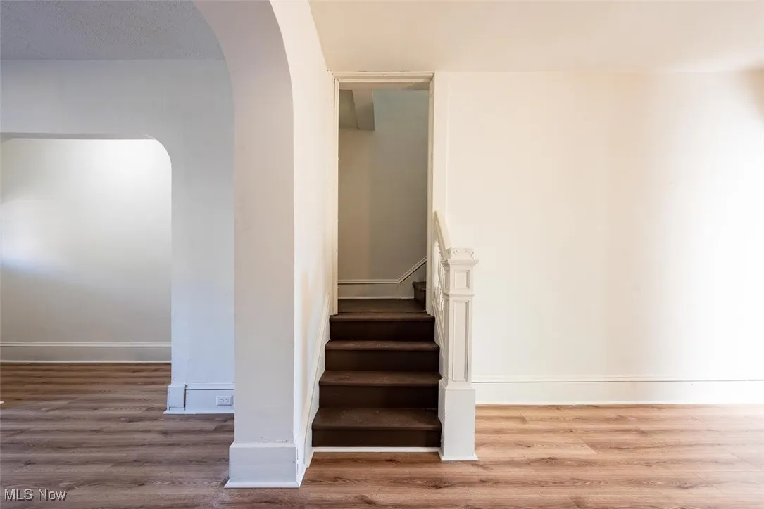 Stairs featuring arched walkways and wood finished floors