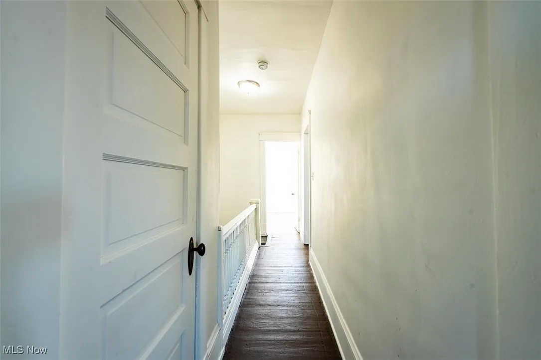 Hallway with an upstairs landing and dark wood-type flooring