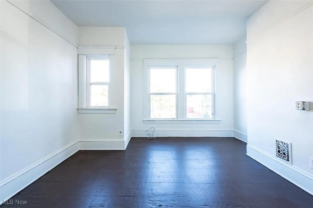 Empty room featuring dark wood-style flooring and baseboards
