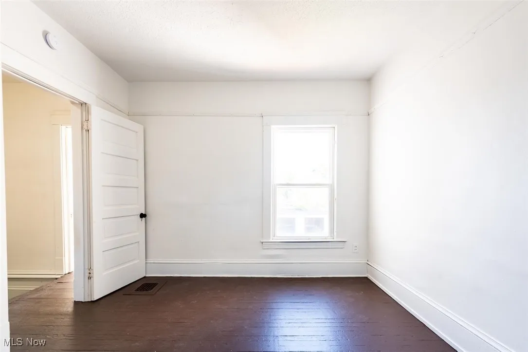 Unfurnished room with dark wood-style floors and baseboards