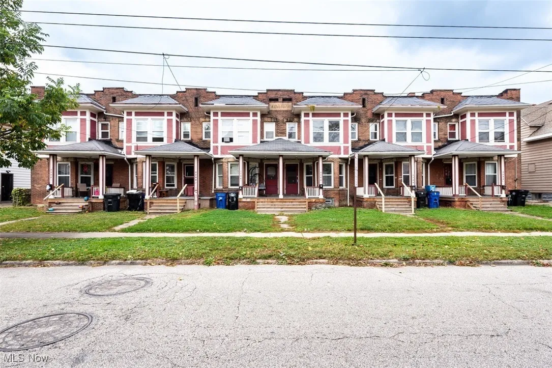 Victorian home with a front lawn, a porch, and brick siding