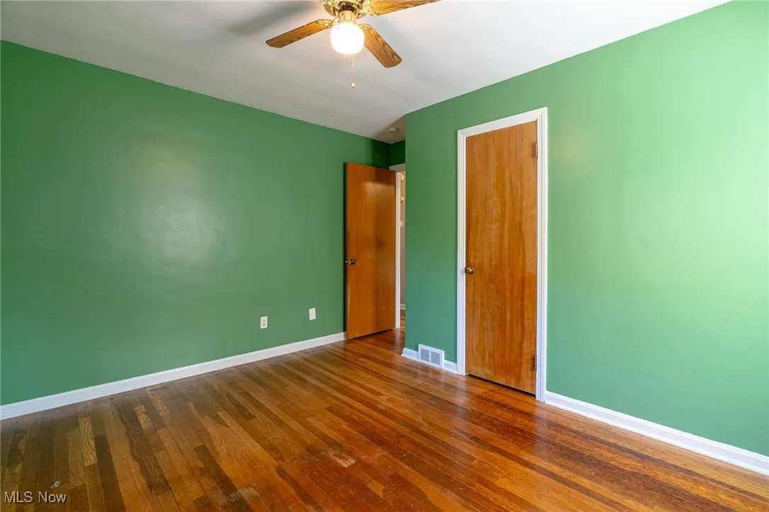 Unfurnished bedroom with dark wood-style flooring, a closet, and ceiling fan