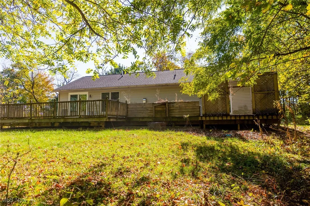 Back of house featuring a wooden deck and a lawn