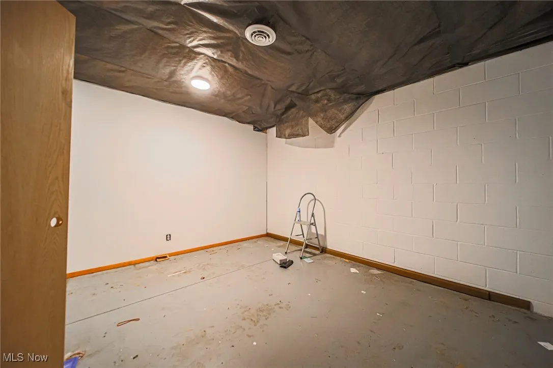 Unfinished basement with baseboards and concrete block wall