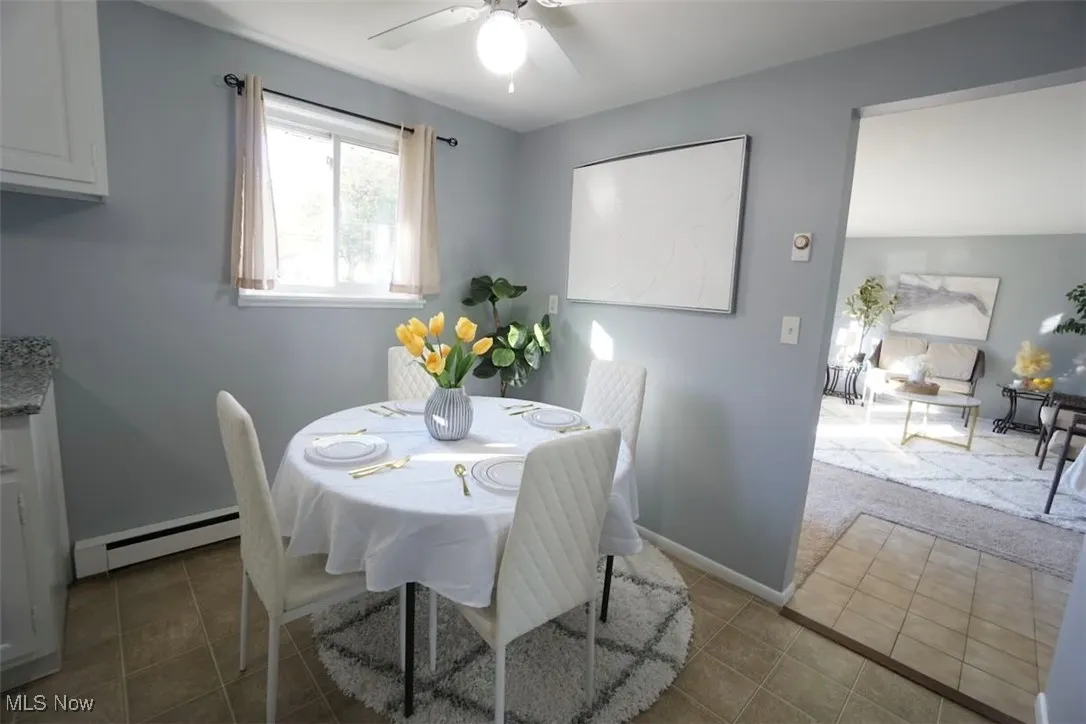 Tiled eat-in kitchen with a baseboard heating unit and ceiling fan
