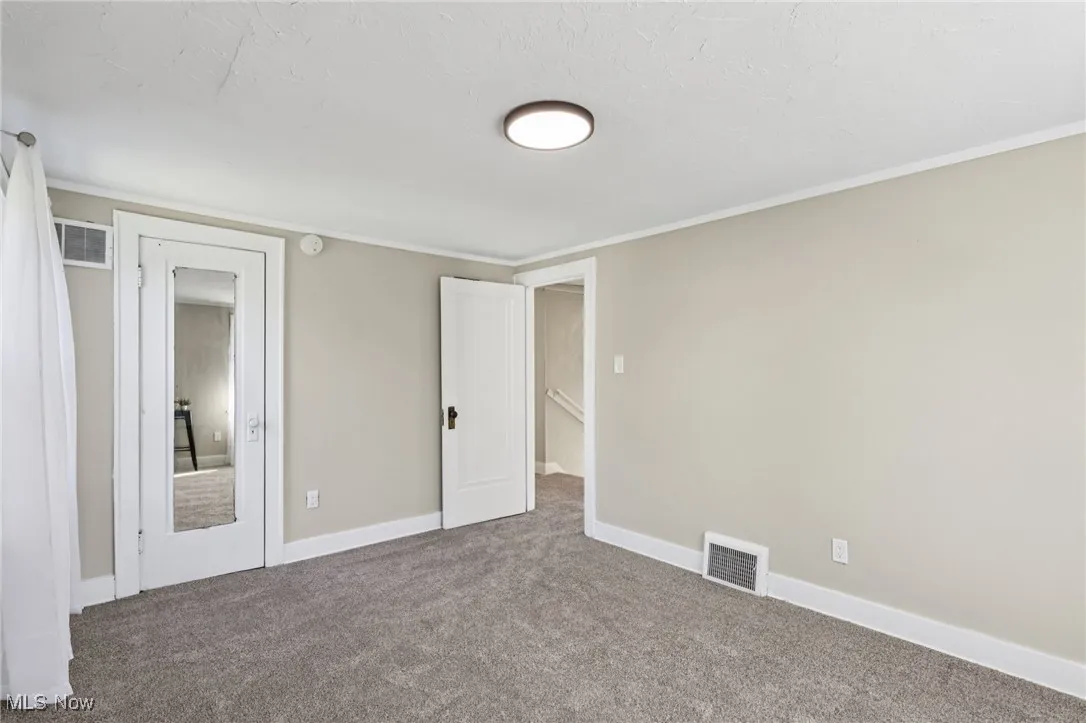 Unfurnished bedroom with carpet flooring, ornamental molding, and a textured ceiling