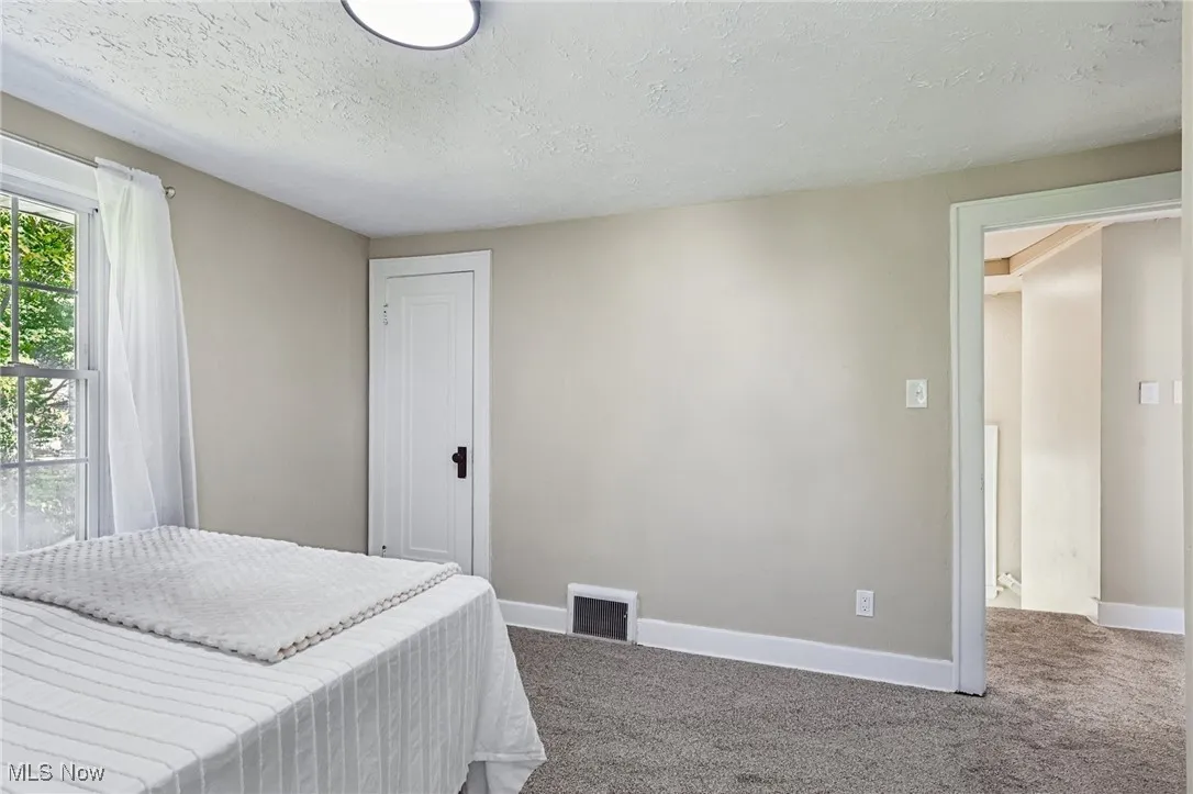 Carpeted bedroom featuring baseboards and a textured ceiling