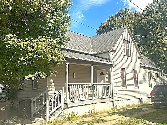 View of side of home with roof with shingles and covered porch