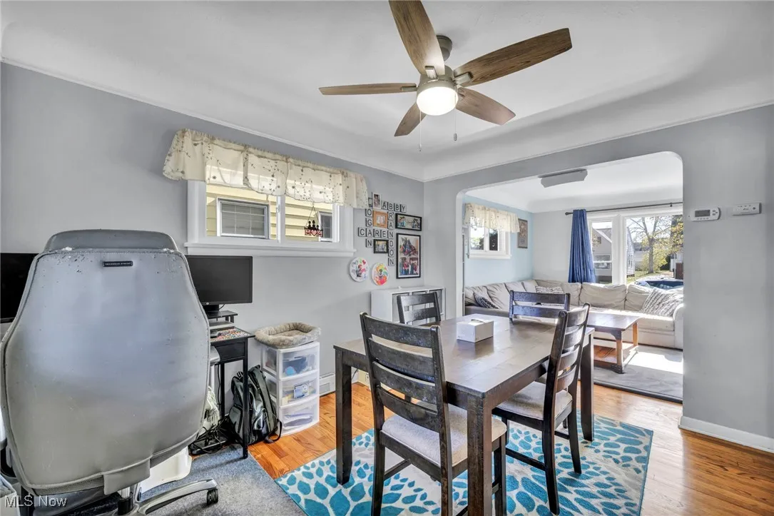 Dining area featuring wood finished floors, arched walkways, and a ceiling fan