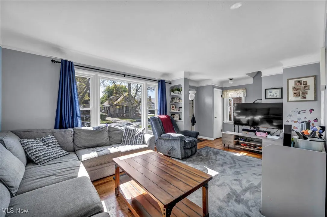 Living room featuring healthy amount of natural light, wood finished floors, and crown molding