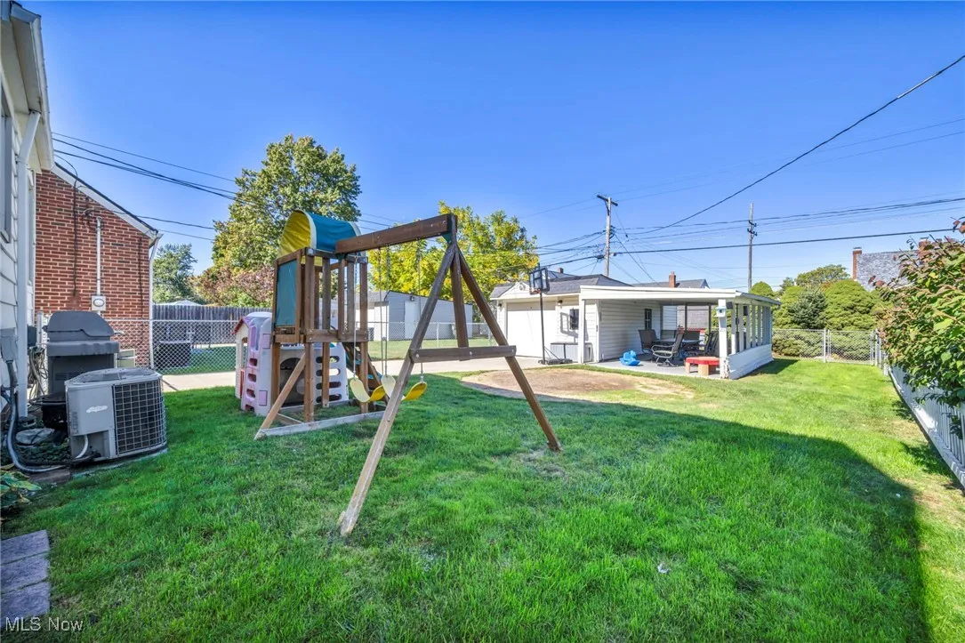 Fenced backyard with a playground and a patio area
