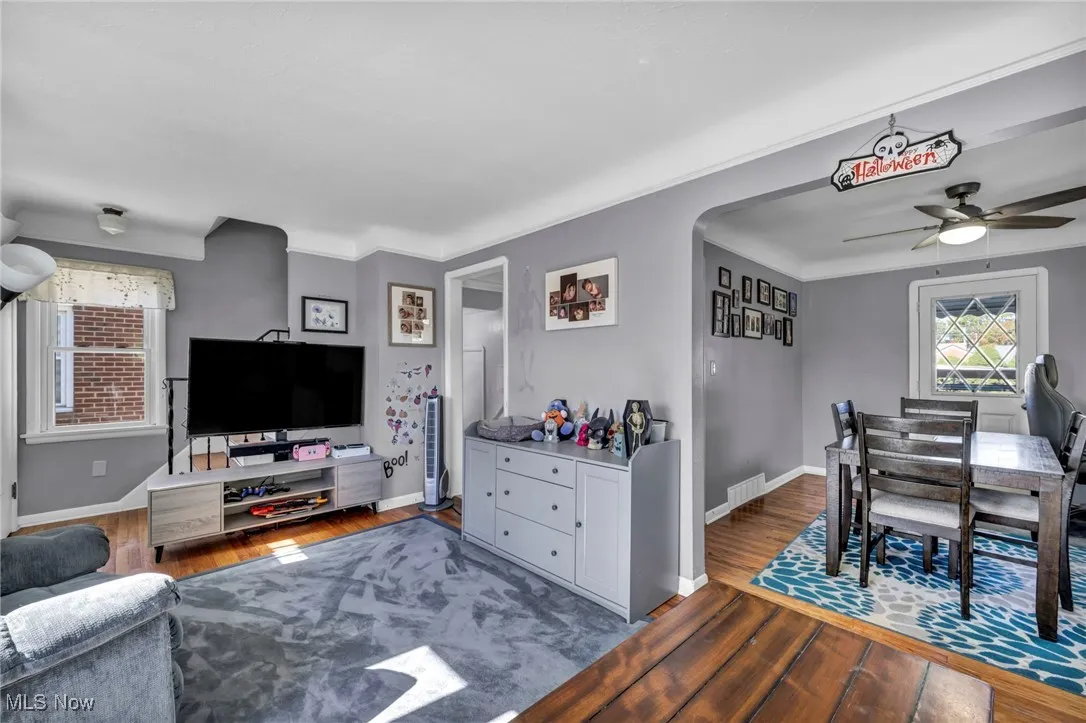 Living room featuring arched walkways, wood finished floors, and ceiling fan