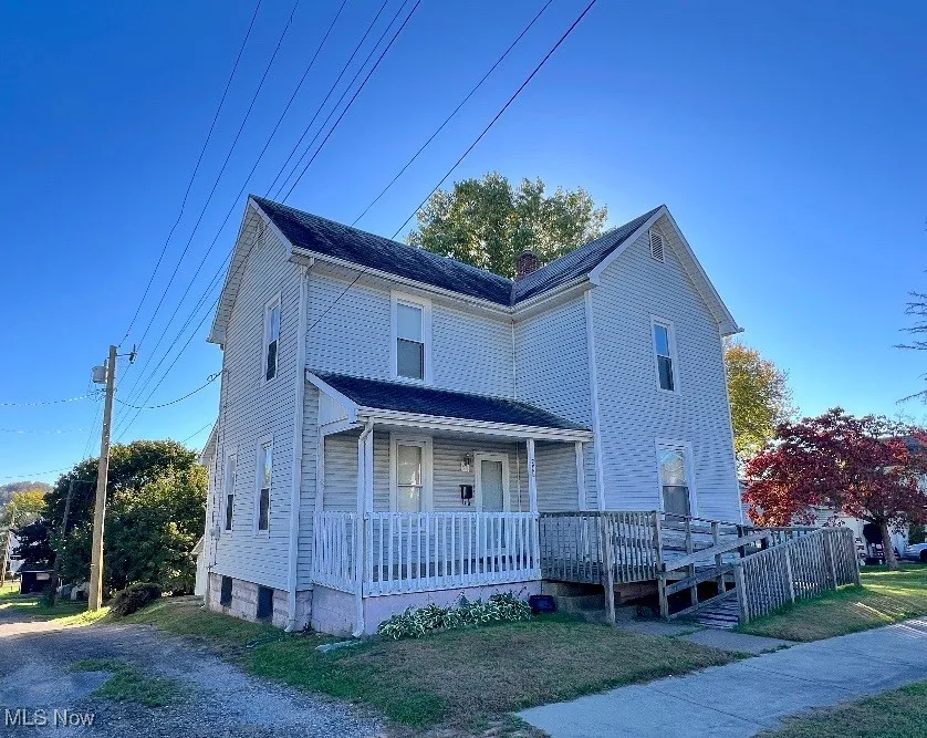 View of front of property with a chimney, a front yard, and a deck