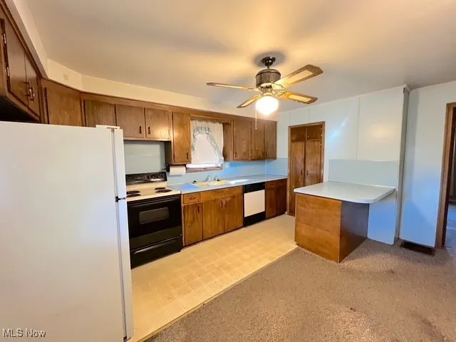 Kitchen featuring freestanding refrigerator, range with electric cooktop, light countertops, brown cabinetry, and dishwashing machine