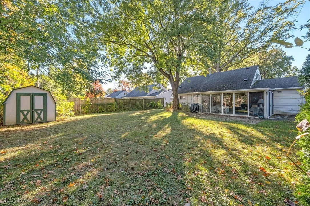 Fenced backyard featuring a storage unit and a patio