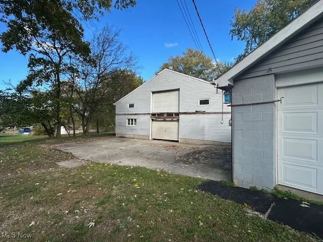 View of side of home featuring an outdoor structure, concrete block siding, and a lawn
