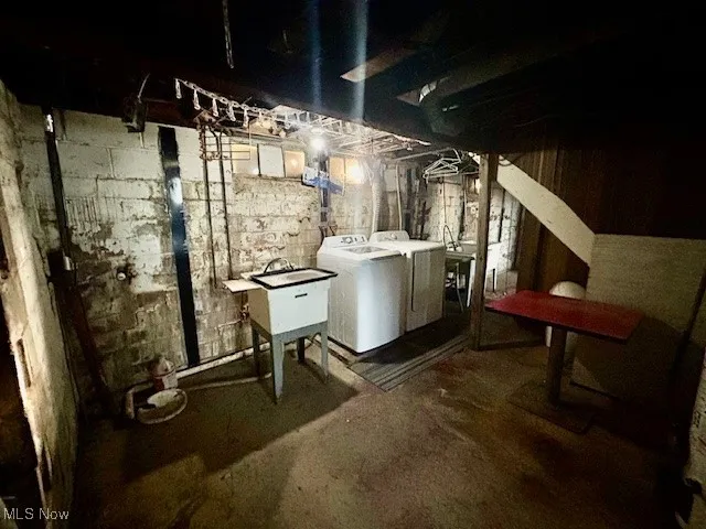 Unfinished below grade area with washing machine and clothes dryer