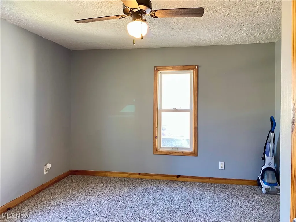 Spare room featuring a textured ceiling, carpet floors, and a ceiling fan