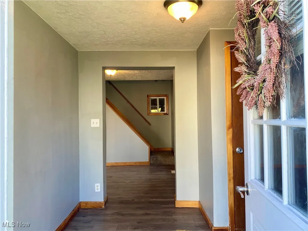 Hallway featuring a textured ceiling and dark wood finished floors