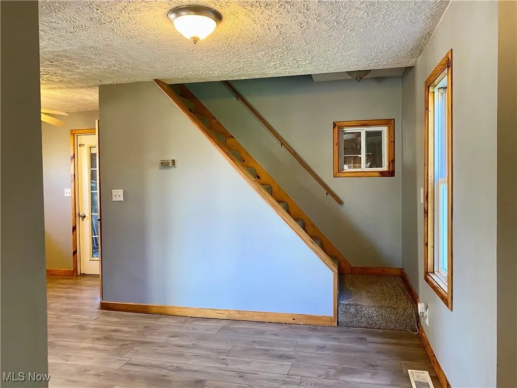 Stairway featuring a textured ceiling and wood finished floors