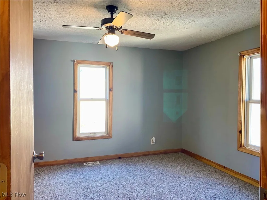 Carpeted spare room with a textured ceiling and ceiling fan