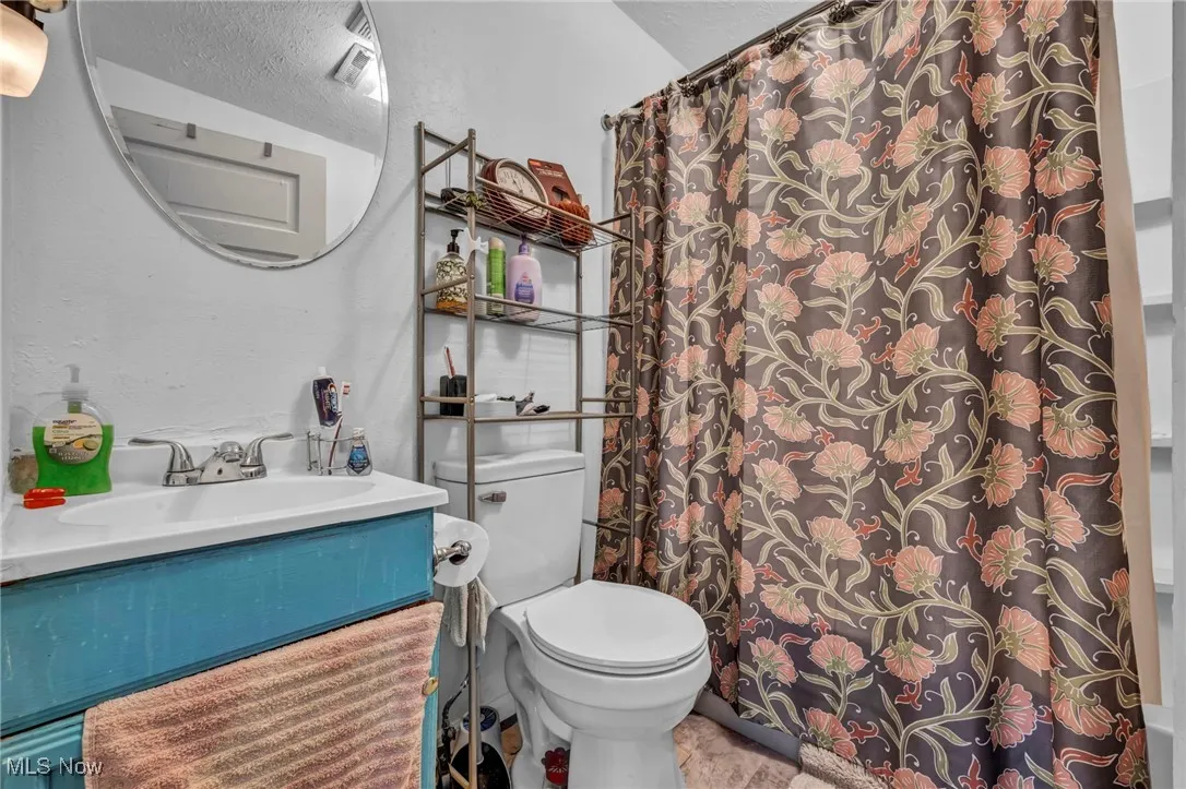 Bathroom with vanity, a textured wall, and shower / tub combo with curtain