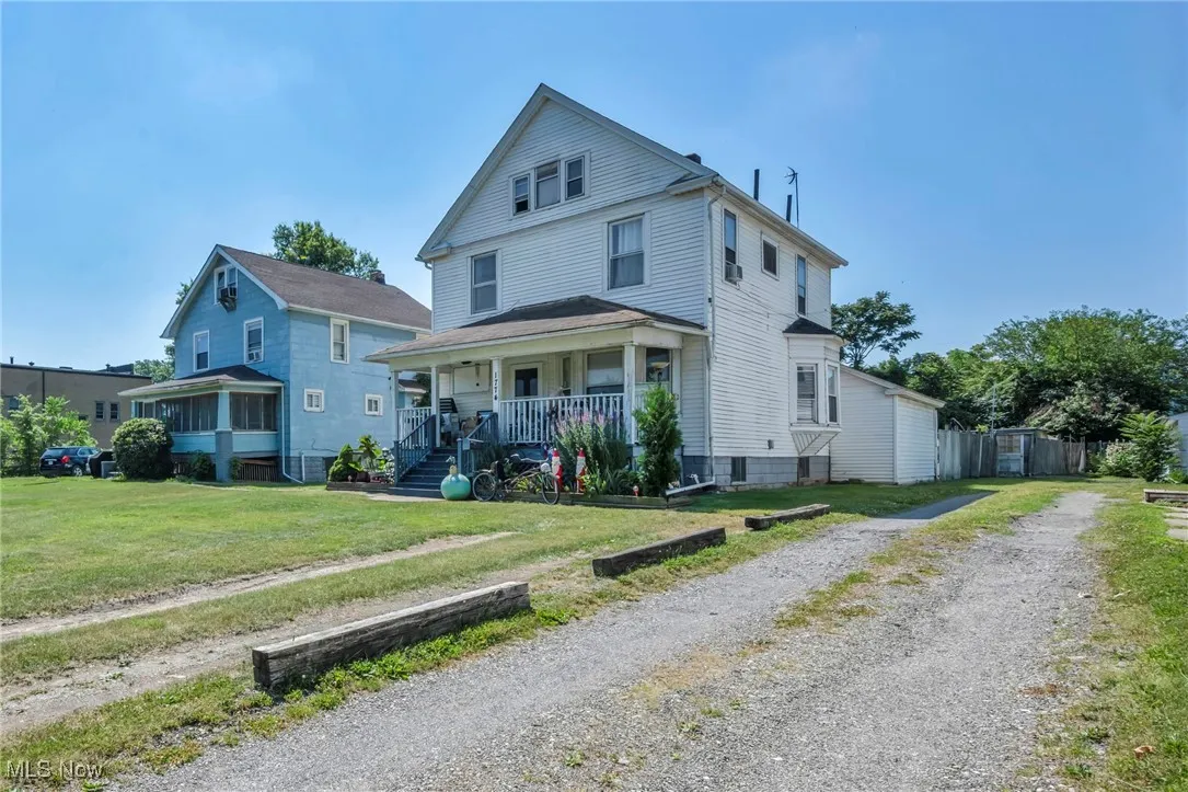 American foursquare style home featuring a porch, a front yard, and driveway