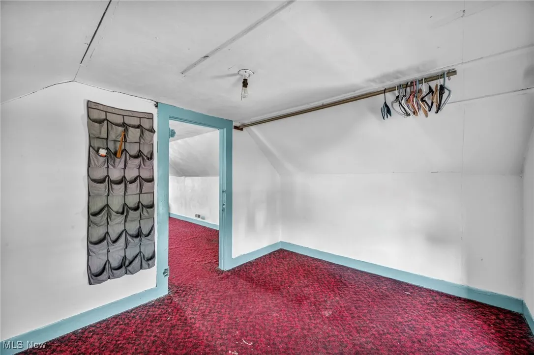 Carpeted empty room with vaulted ceiling