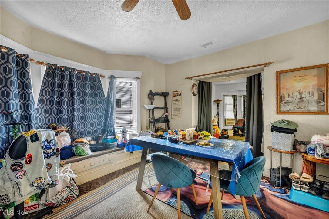 Dining space with a textured ceiling, carpet flooring, and ceiling fan