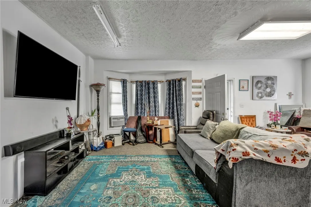Living area featuring carpet, a textured ceiling, and cooling unit