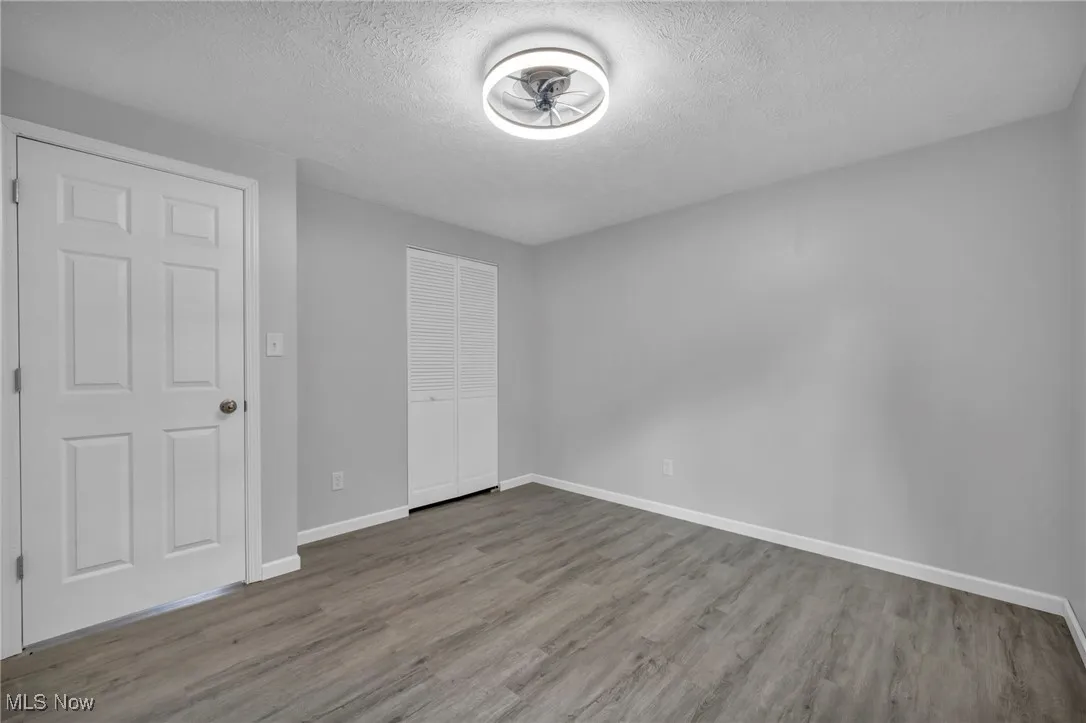 Unfurnished bedroom featuring a textured ceiling, wood finished floors, and a closet