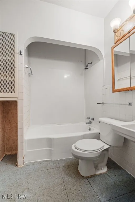 Bathroom with shower / washtub combination, tile walls, and tile patterned floors