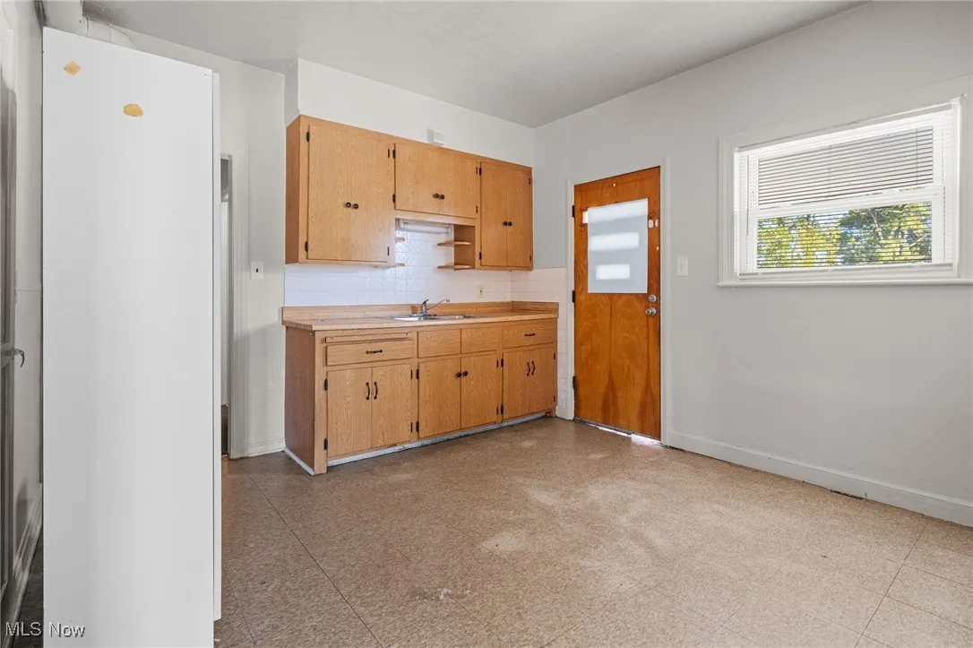 Kitchen with light floors, tasteful backsplash, light countertops, and open shelves