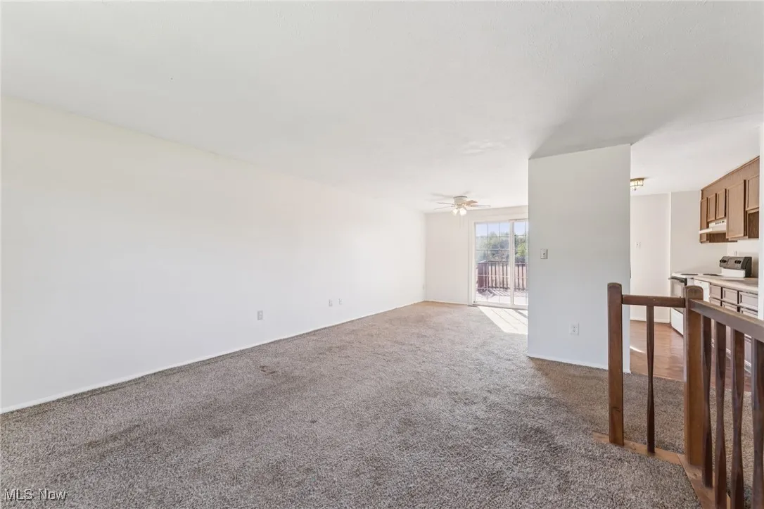 Unfurnished living room featuring dark colored carpet and baseboards