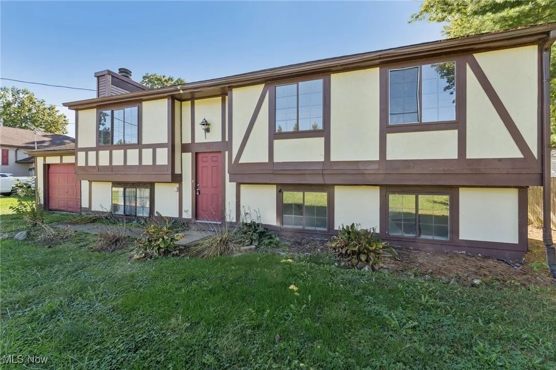 View of front of house with stucco siding, a front lawn, and a chimney