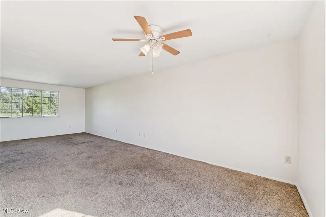 Empty room with carpet flooring and a ceiling fan