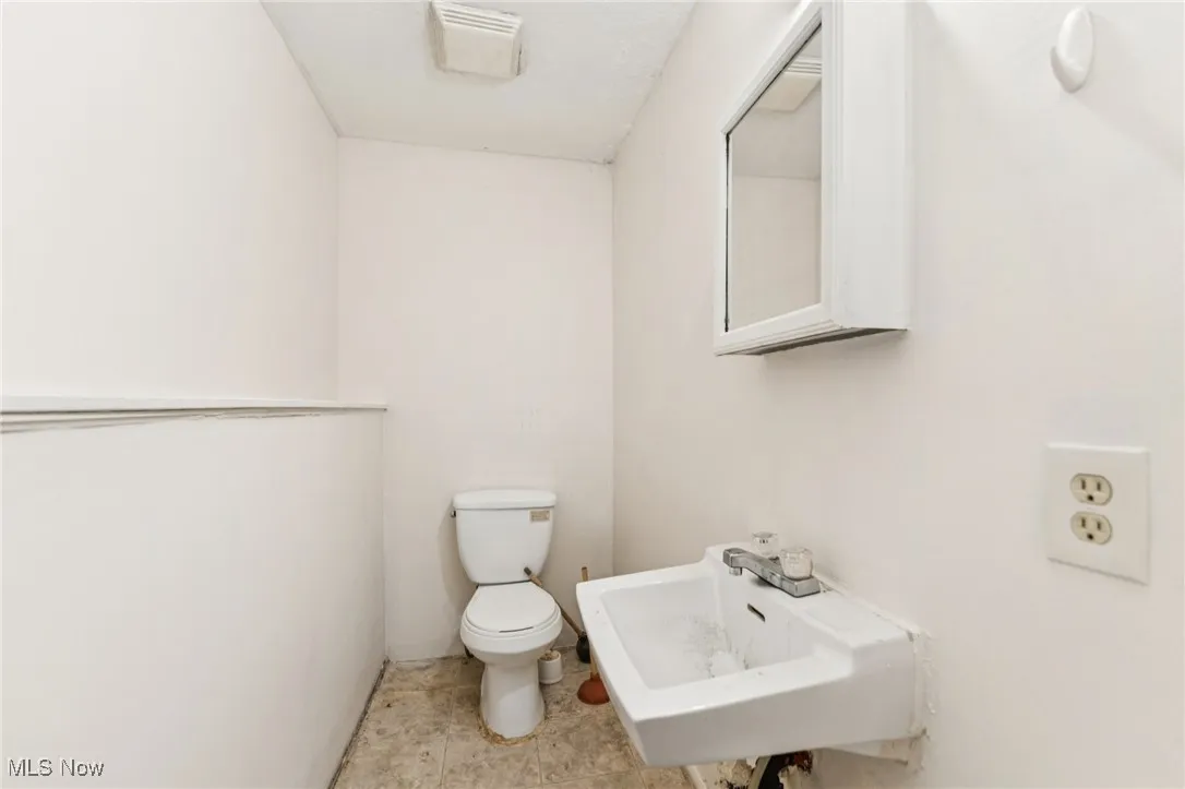 Half bath featuring toilet and light tile patterned flooring