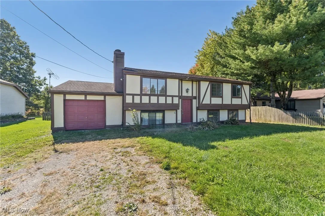 View of front facade featuring an attached garage, a chimney, stucco siding, and driveway