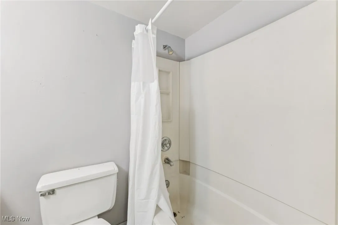 Bathroom featuring shower / bath combination with curtain and toilet