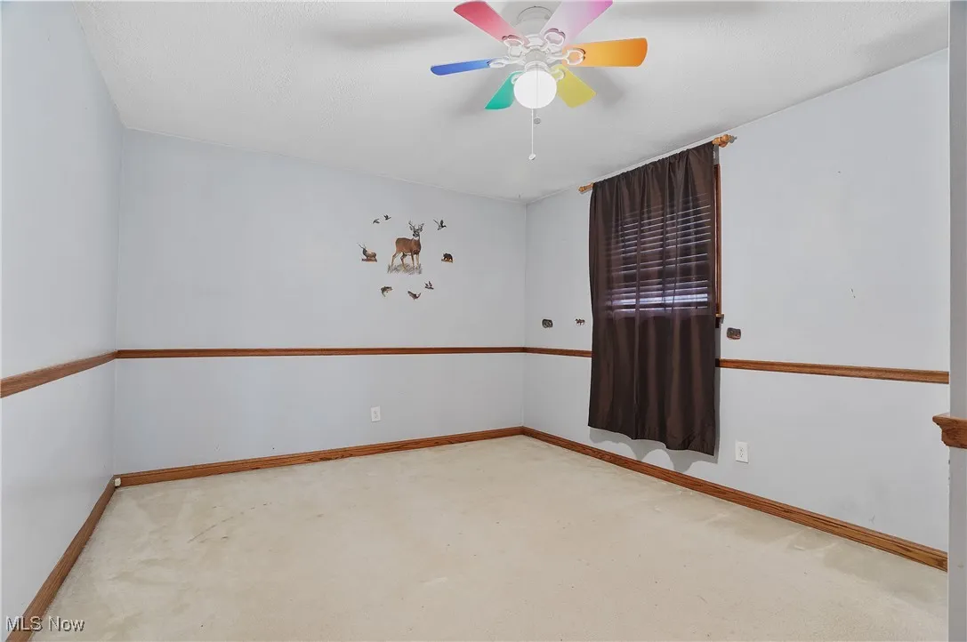 Carpeted empty room with baseboards and ceiling fan