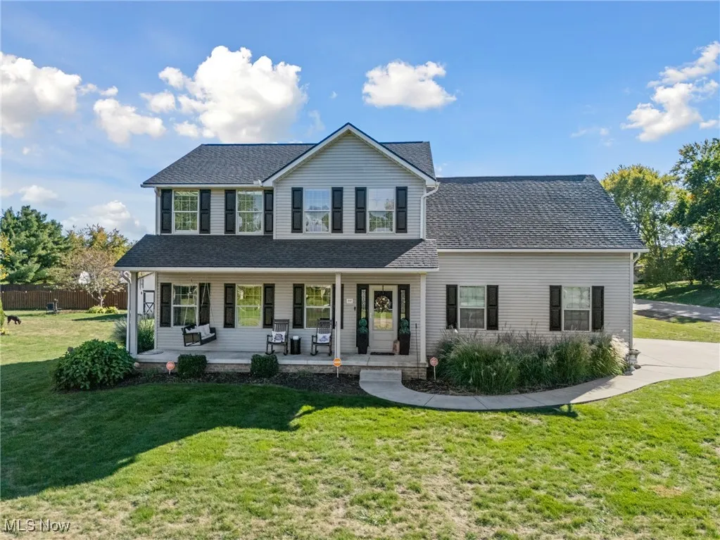View of front of home with covered porch, a front lawn, and roof with shingles