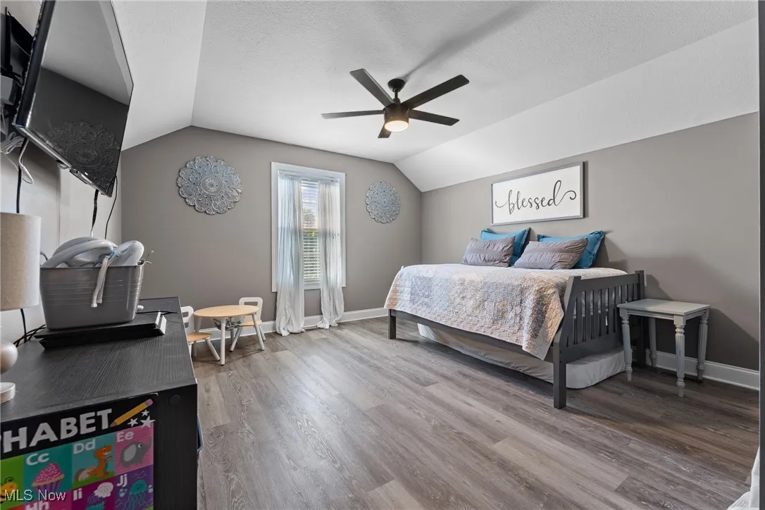 Bedroom with lofted ceiling, a ceiling fan, light wood finished floors, and a textured ceiling
