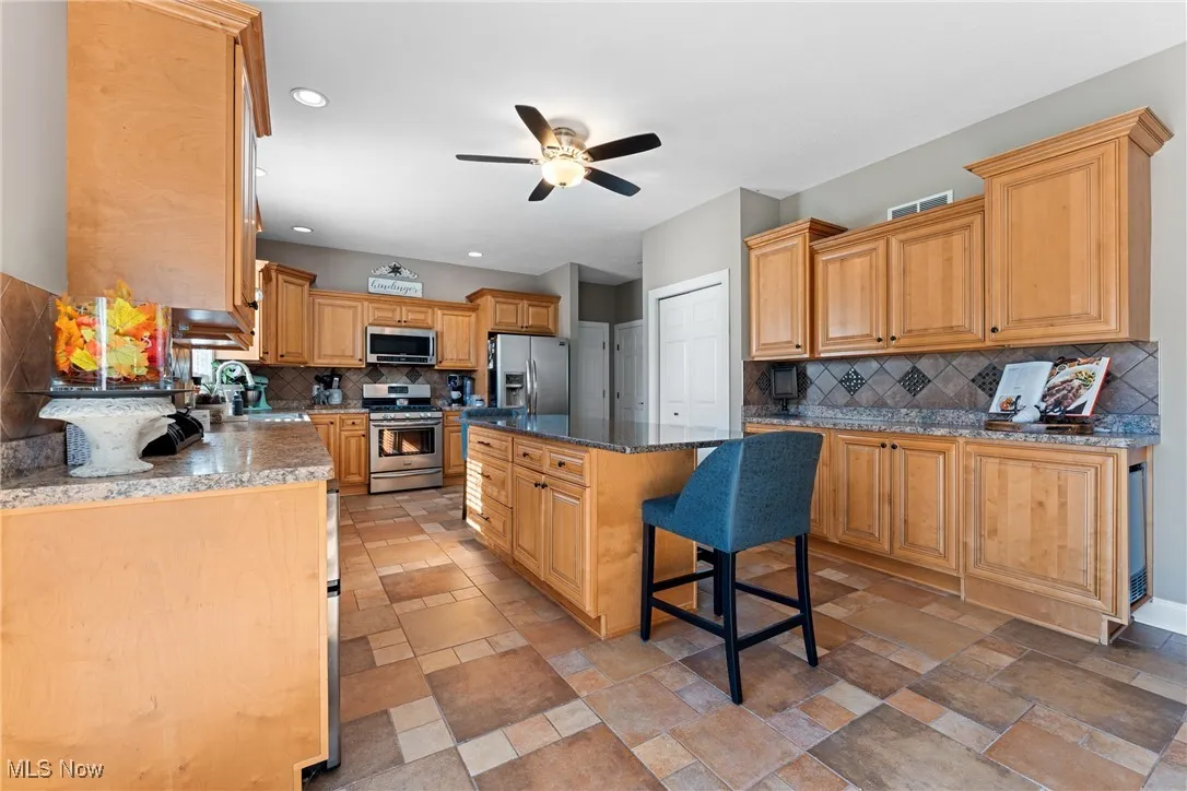 Kitchen featuring appliances with stainless steel finishes, a kitchen bar, tasteful backsplash, a kitchen island, and recessed lighting