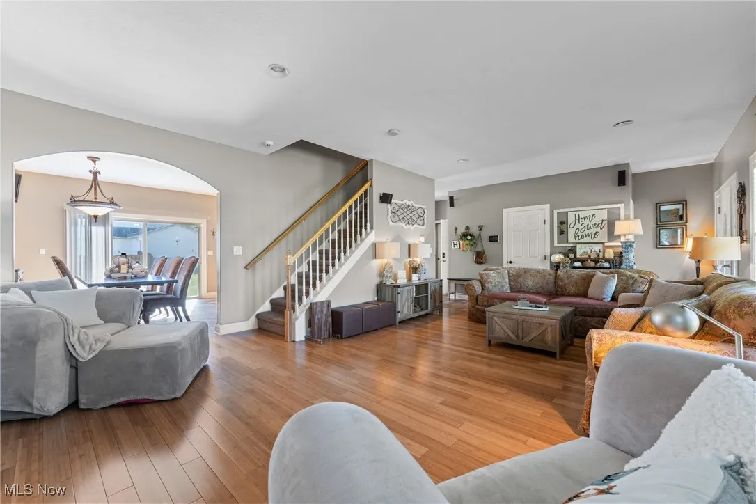 Living area with hardwood / wood-style floors, stairway, arched walkways, and recessed lighting