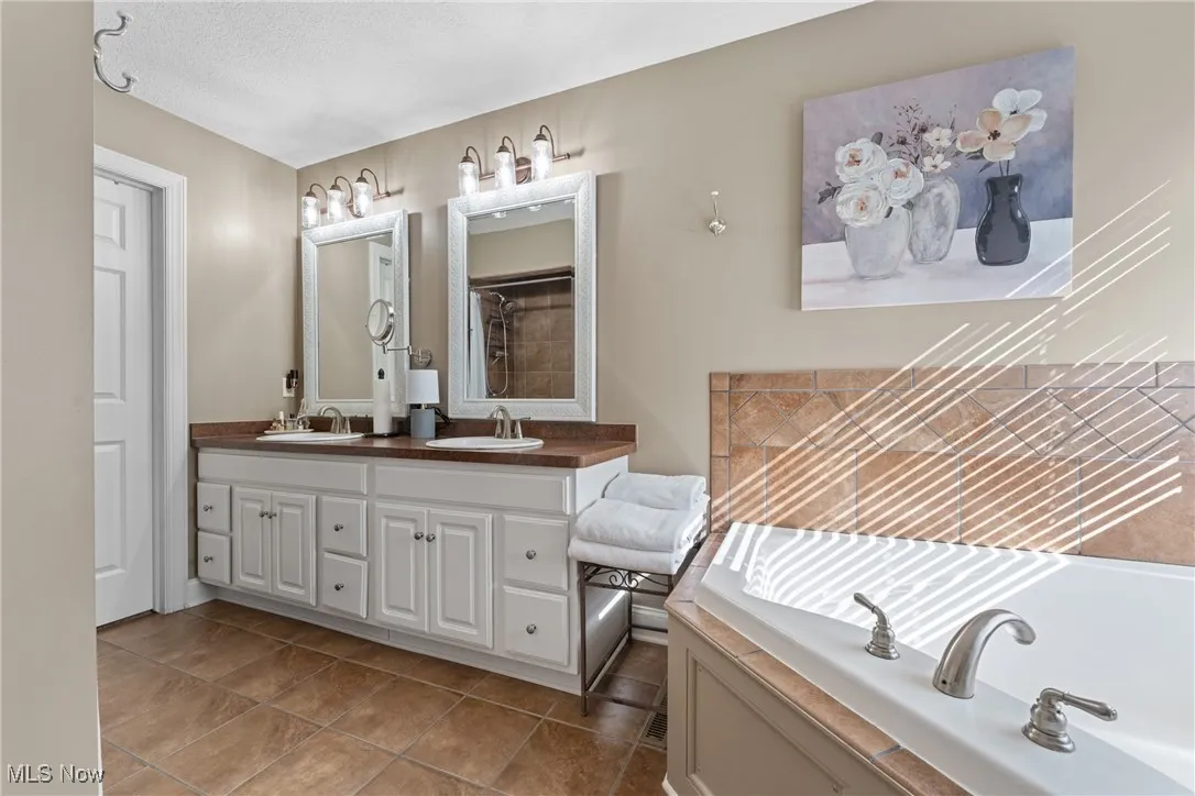 Full bath with a bath, double vanity, light tile patterned floor, and walk in closet